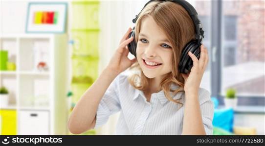 technology and music concept - happy smiling girl with headphones over home room background. happy smiling girl with headphones at home