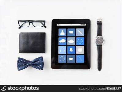 technology and objects concept - tablet pc computer with application icons, wallet, eyeglasses, bowtie and wristwatch on table