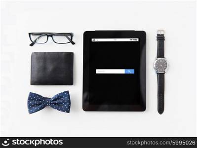technology and objects concept - tablet pc computer with internet search bar, wallet, eyeglasses, bowtie and wristwatch on table