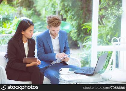 technology and office concept - two business man and woman with laptop - tablet pc computer and clipboard document having discussion in office.