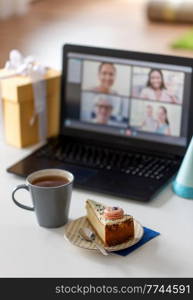 technology and online party concept - piece of birthday cake on plate and laptop computer with video call on screen at home. birthday cake and laptop with video call on screen