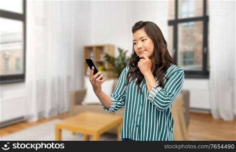 technology and people concept - asian woman using smartphone over home background. asian woman using smartphone at home