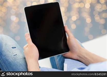 technology and people concept - close up of male hands holding tablet pc computer over holidays lights background. close up of male hands holding tablet pc