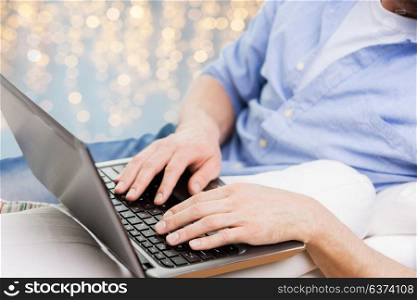 technology and people concept - close up of man typing on laptop keyboard over holidays lights background. close up of man typing on laptop keyboard