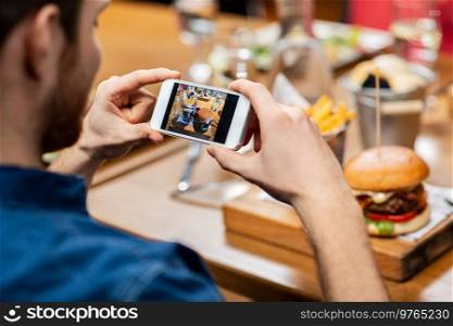 technology and people concept - close up of man with smartphone photographing food at restaurant. man with phone photographing food at restaurant