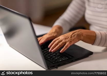 technology and people concept - close up of senior woman hands typing on laptop at home. hands of senior woman typing on laptop at home