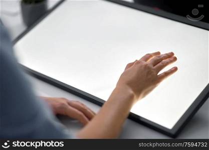 technology and people concept - hand on led light tablet or touch screen at night office. hand on led light tablet at night office