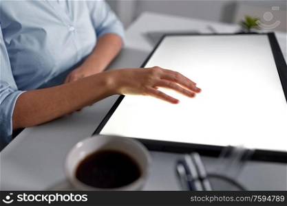 technology and people concept - hand on led light tablet or touch screen at night office. hand on led light tablet at night office