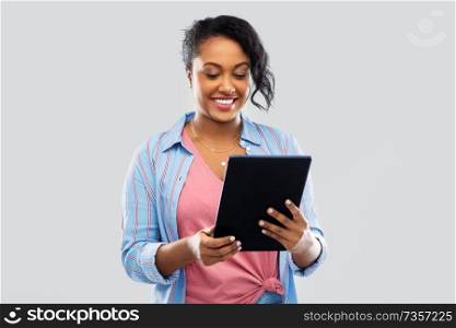 technology and people concept - happy african american woman using tablet computer over grey background. happy african american woman using tablet pc