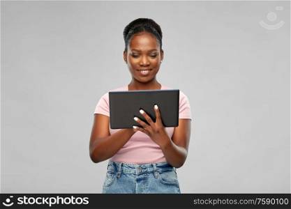 technology and people concept - happy african american woman using tablet computer over grey background. happy african american woman using tablet pc