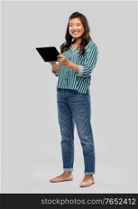 technology and people concept - happy asian woman using tablet computer over grey background. happy asian woman using tablet computer