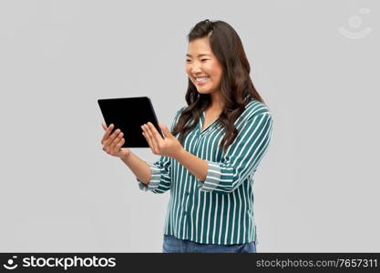 technology and people concept - happy asian woman using tablet computer over grey background. happy asian woman using tablet computer