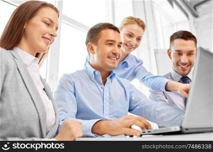 technology and people concept - happy business team with laptop computer in office. happy business team with laptop computer in office