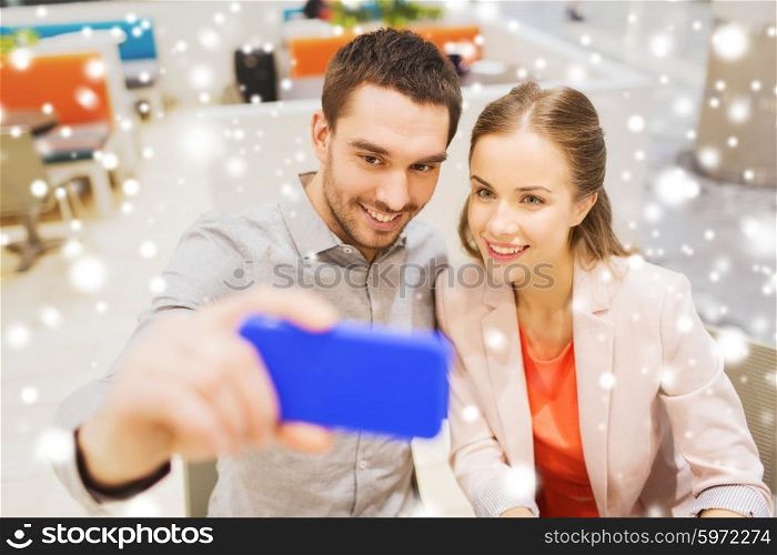 technology and people concept - happy couple taking selfie with smartphone in mall or cafe with snow effect. happy couple taking selfie with smartphone in cafe