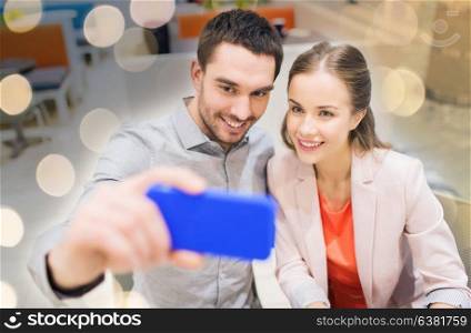 technology and people concept - happy couple taking selfie with smartphone in mall or cafe. happy couple taking selfie with smartphone in cafe
