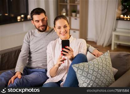 technology and people concept - happy couple with smartphone taking selfie in bed at home. happy couple with smartphone taking selfie at home