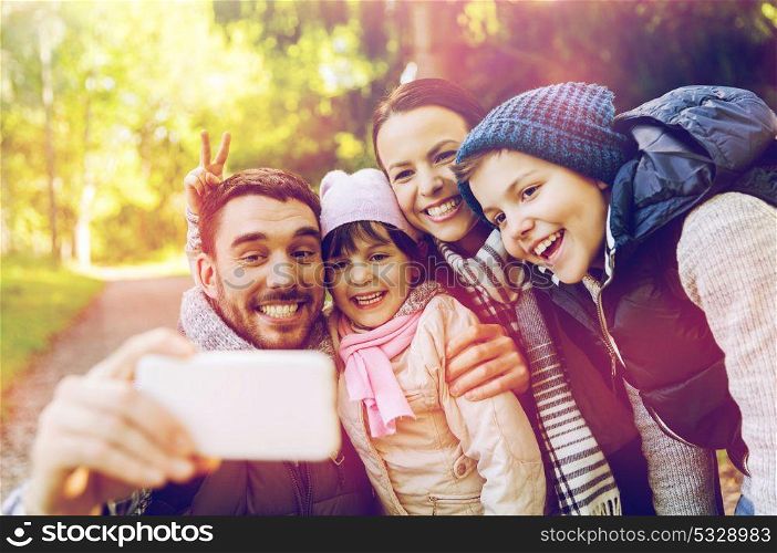 technology and people concept - happy family taking selfie by smartphone outdoors. happy family taking selfie by smartphone outdoors