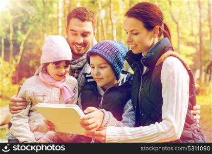 technology and people concept - happy family with tablet pc computer at camp in woods. happy family with tablet pc at camp