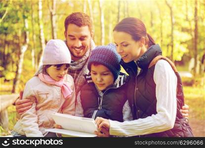 technology and people concept - happy family with tablet pc computer at camp in woods. happy family with tablet pc at camp