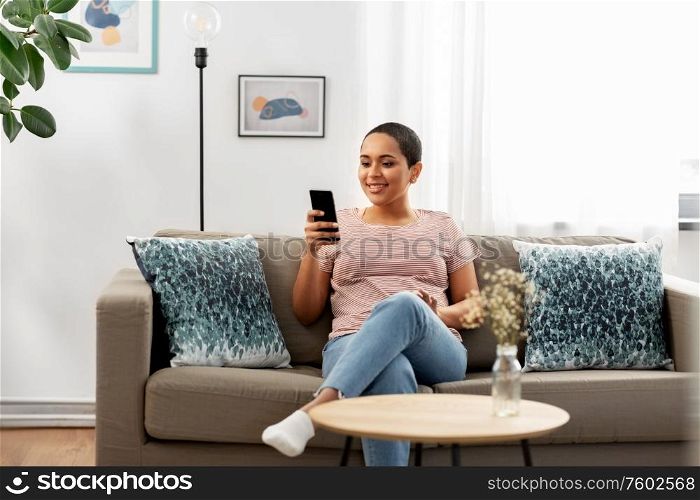 technology and people concept - happy smiling african american woman in glasses with smartphone at home. african american woman with smartphone at home