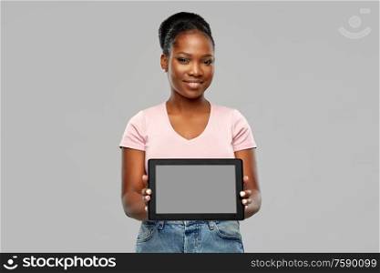 technology and people concept - happy smiling african american woman showing tablet pc computer over grey background. happy african american woman showing tablet pc