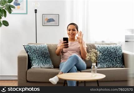 technology and people concept - happy smiling african american woman with smartphone having video call at home. woman with smartphone having video call at home