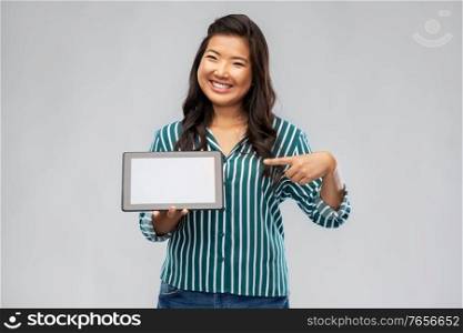 technology and people concept - happy smiling asian woman using tablet computer over grey background. happy asian woman using tablet computer
