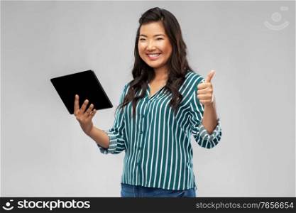 technology and people concept - happy smiling asian woman with tablet computer showing thumbs up over grey background. happy asian woman with tablet pc showing thumbs up