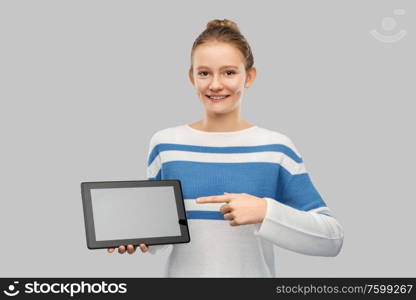 technology and people concept - happy smiling teenage girl in pullover showing tablet pc computer over grey background. happy smiling teenage girl with tablet computer