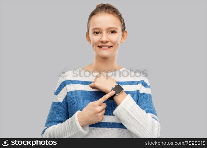 technology and people concept - happy smiling teenage girl in pullover with smart watch over grey background. happy smiling teenage girl with smart watch