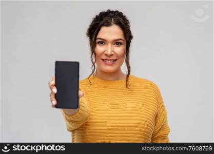 technology and people concept - happy smiling woman showing smartphone over grey background. happy woman showing smartphone