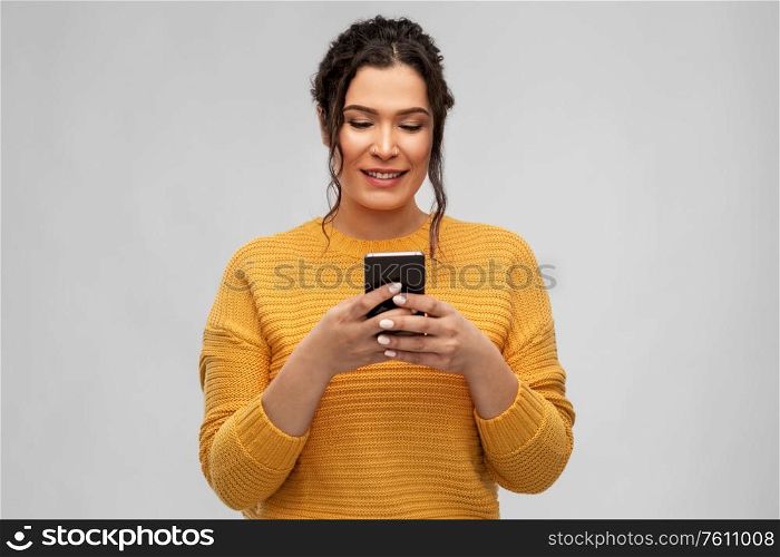 technology and people concept - happy smiling woman using smartphone over grey background. happy woman using smartphone