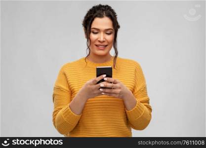 technology and people concept - happy smiling woman using smartphone over grey background. happy woman using smartphone