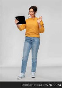technology and people concept - happy woman having video call on tablet computer over grey background. happy young woman having video call on tablet pc