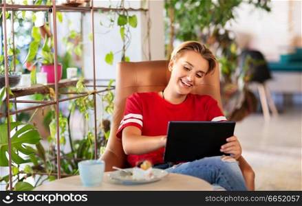 technology and people concept - happy woman or teenage girl with tablet pc computer and cake at cafe or coffee shop. happy woman with tablet pc at cafe or coffee shop