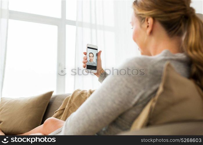 technology and people concept - happy woman with smartphone taking selfie at home. woman taking smartphone selfie at home