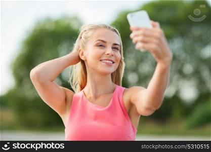 technology and people concept - happy young beautiful woman with smartphone taking selfie outdoors. happy woman taking selfie with smartphone outdoors