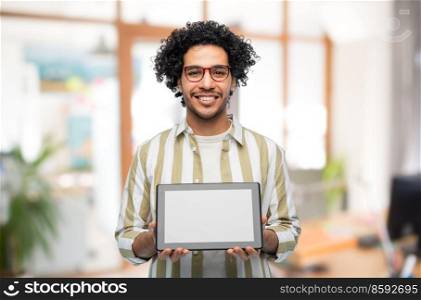 technology and people concept - happy young man in glasses with tablet pc computer over office background. happy young man with tablet pc computer at office