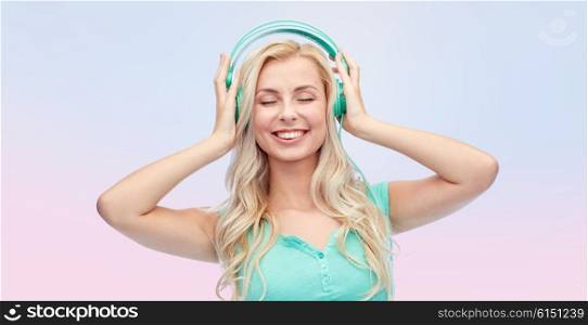 technology and people concept - happy young woman or teenage girl with headphones listening to music over rose quartz and serenity gradient background. happy young woman or teenage girl with headphones