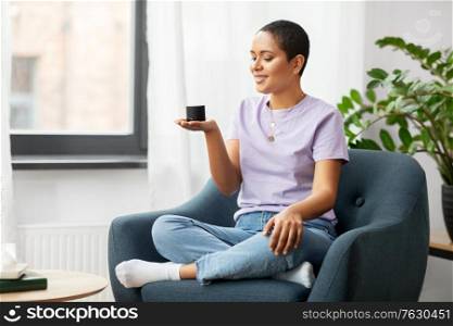 technology and people concept - smiling african american woman in glasses with smart speaker at home. african american woman with smart speaker at home