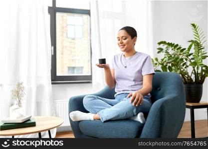technology and people concept - smiling african american woman in glasses with smart speaker at home. african american woman with smart speaker at home
