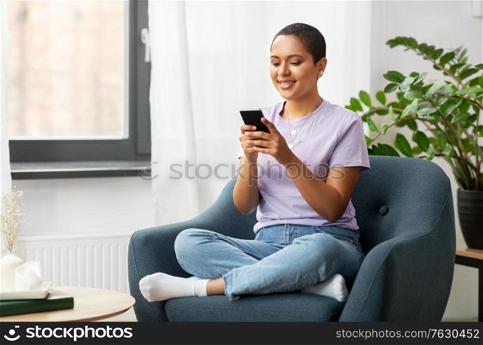 technology and people concept - smiling african american woman in glasses with smartphone at home. african american woman with smartphone at home