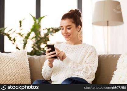 technology and people concept - smiling woman with smartphone at home. woman with smartphone at home