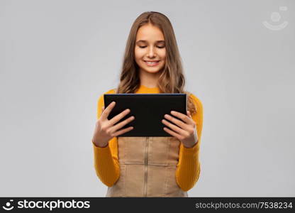 technology and people concept - teenage girl using tablet computer over grey background. teenage girl using tablet computer