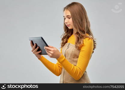 technology and people concept - teenage girl using tablet computer over grey background. teenage girl using tablet computer