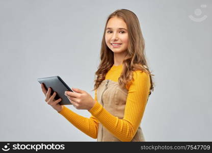 technology and people concept - teenage girl using tablet computer over grey background. teenage girl using tablet computer