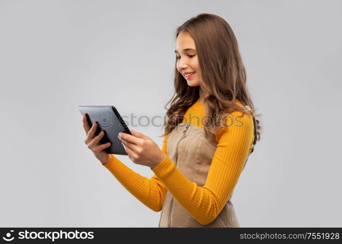 technology and people concept - teenage girl using tablet computer over grey background. teenage girl using tablet computer