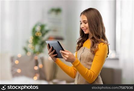 technology and people concept - teenage girl using tablet computer over home background. teenage girl using tablet computer at home