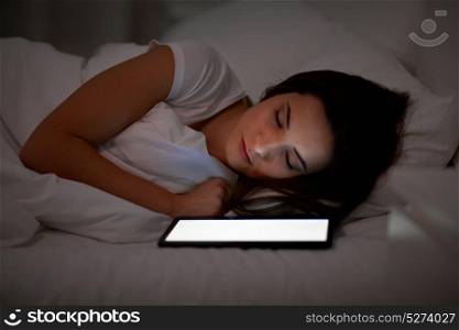 technology and people concept - young woman with tablet pc computer sleeping in bed at home at night. woman with tablet pc sleeping in bed at night
