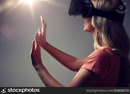 technology, augmented reality, entertainment and people concept - close up of happy young woman with virtual reality headset or 3d glasses touching something invisible. close up of woman in virtual reality headset